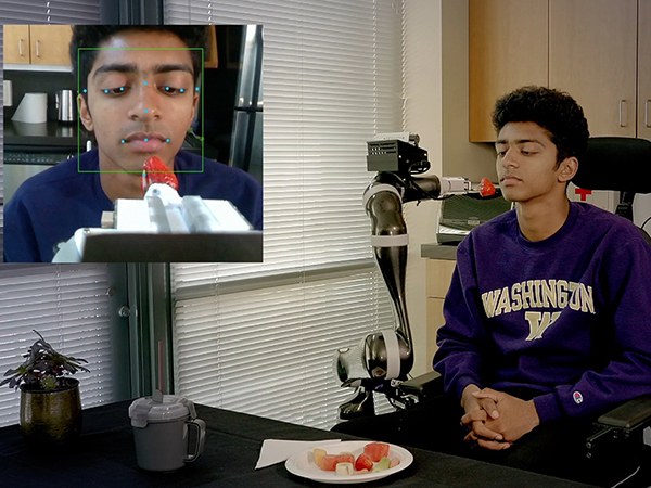 group-lab-personal-robotics-lab-feeding-perception Robotic arm feeding seated person a strawberry on a fork with an inset image of the robot mapping features of their face