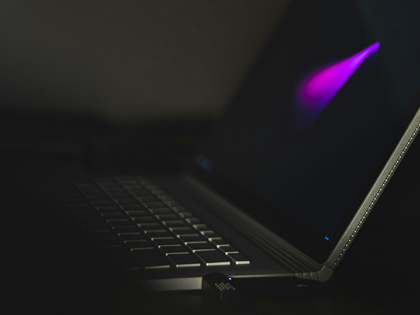 group-lab-security-privacy Laptop displaying glowing purple light onscreen in darkened room